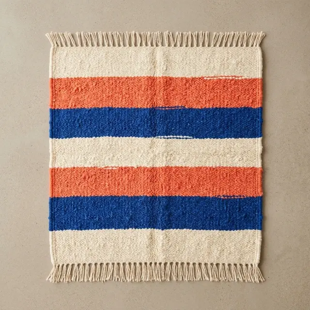 Handwoven cream, coral, and cobalt striped rug viewed from above