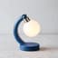 A compact cobalt arch desk lamp with a glowing opal diffuser