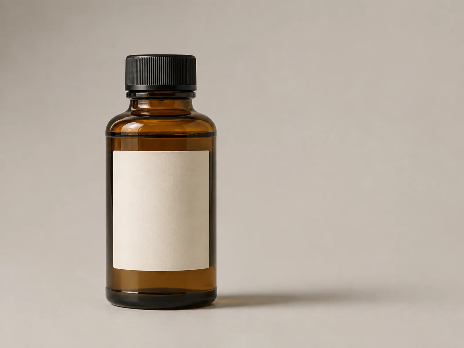 Unbranded amber glass bottle on a neutral studio background before editing